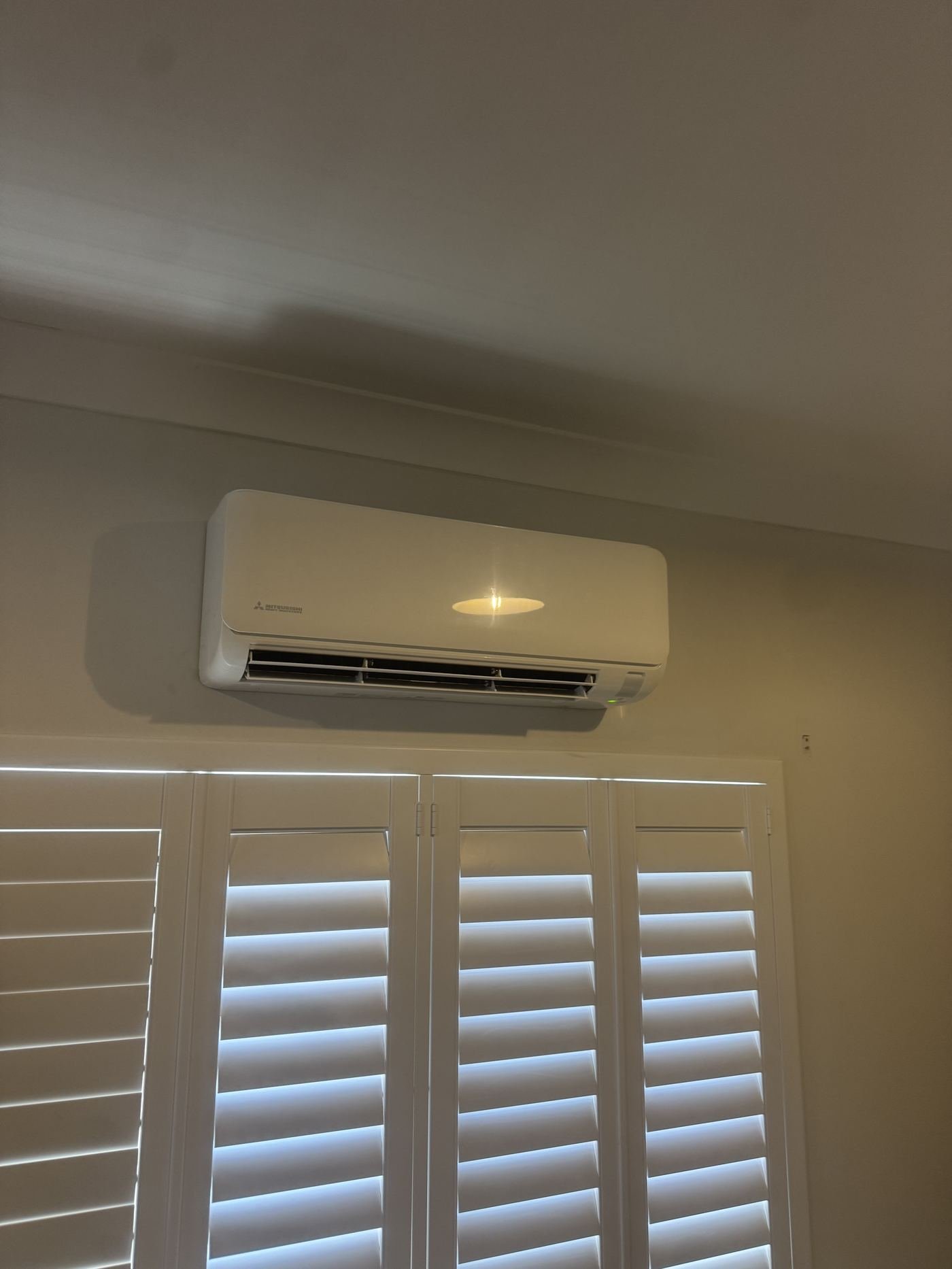 Indoor split-system unit mounted above plantation shutters